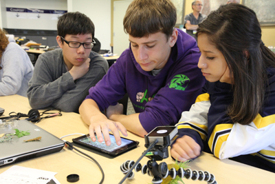 Three students working together on a tablet.