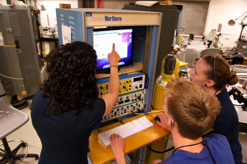 An instructor points out data on a monitor to two students in the Neurobiology lab at the University of Washington. 