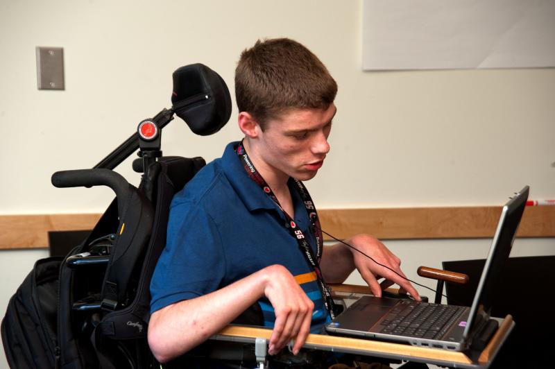 Image of student who uses a wheelchair, using a laptop.