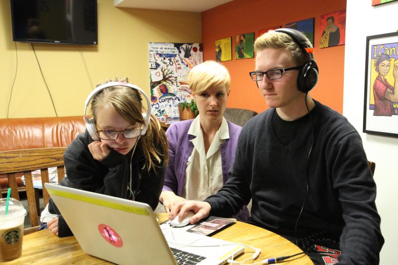 Two students view a computer with a mentor.