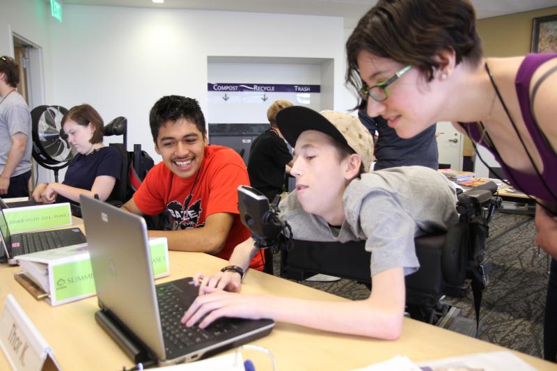 A student uses a laptop while two other students look at the screen.