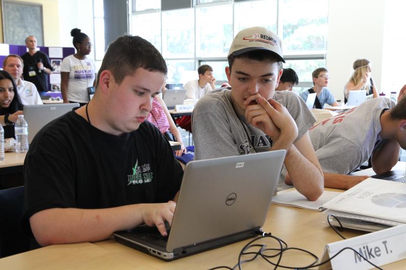 Two male students work together on a computer.