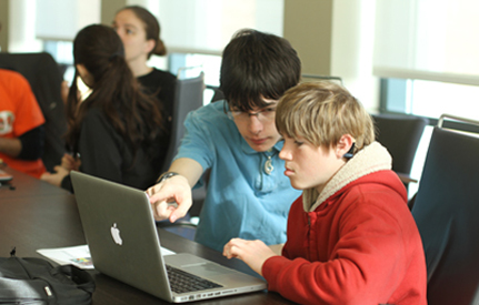 A student who is hearing impaired works on a computer project with another student.