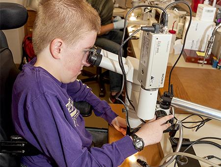 A student reviews a specimen through a microscope.