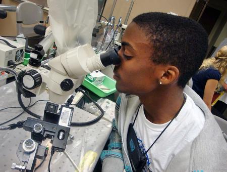 Image of DO-IT Scholar Ryan looking through a microscope during a microbiology lab.