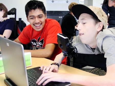 Image of two students working together on a laptop.