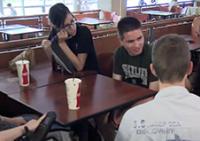 Students sit around a table in the cafeteria.