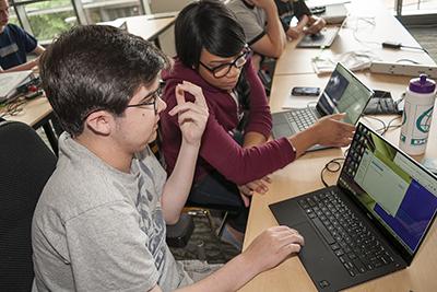 Two students help each other on the computer.