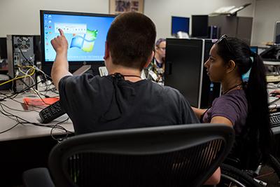 A student helps his peer on the computer.