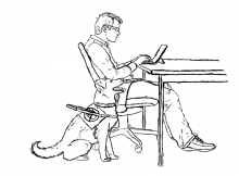 A man working on a computer with his guide dog.