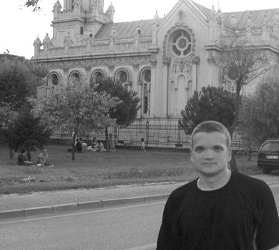 '99 Scholar Stuart in Japan. Picture of Stewart with ornate building in background.