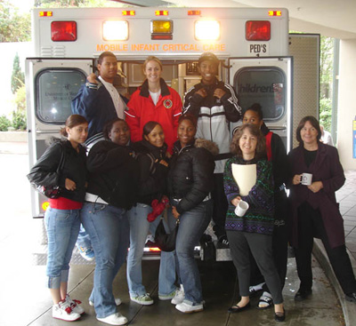 A group of DMD high school students tour an ambulance at Children's Hospital before meeting up with mentors. Group photo of DMD students at the rear of an ambulance.