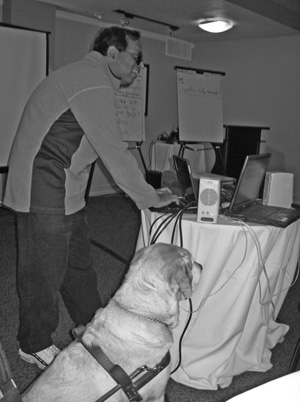 Google's T.V. Raman, at DO-IT's capacity-building institute on web accessibility, accompanied by his service dog Hubble, prepares for his keynote address. Picture of T.V. and Hubble.