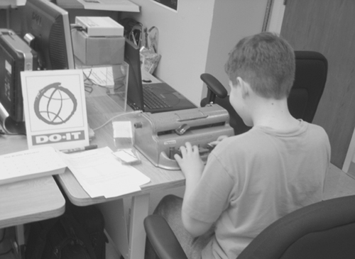 A student uses a Braille machine to type his name at the Engineering Open House. Picture of a student using a braille machine.