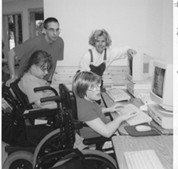 A picture of DO-IT Director Sheryl Burgstahler and Ambassador Kris assisting students using computers at Camp Courage