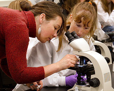 Image of an instructor assisting a student using a microscope