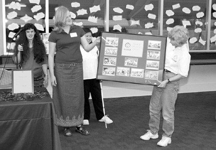 93 Scholars Anna, Katie, and Nhi present Director Sheryl Burgstahler with pictures of all DO-IT Scholars at DO-IT's tenth anniversary party. Picture of presentation of award.