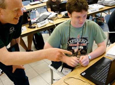 '09 Scholar Ryan works with DO-IT staff Terry in the hands-on computer lab at Summer Study 2009. Picture of Ryan at his laptop while Terry points something out on the screen.