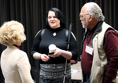 PI Sheryl Burgstahler talks to two individuals at an event.