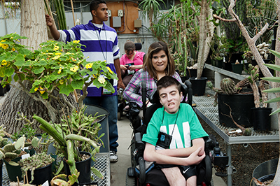 Students with disabilities look at plants in a greenhouse.