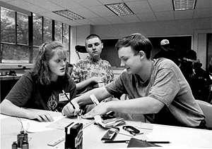 Matt works with Katie and Mark on a project involving Hershey bars and rulers--the measuring kind Picture of DO-IT Scholars working on a project