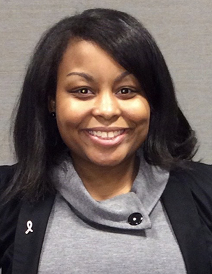 Headshot of a women with black hair and wearing a grey shirt with a black coat