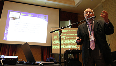 A presenter speaks in front of a powerpoint.