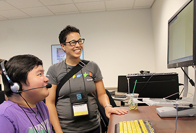 A staff members teaches a students how to use a voice to text program. 