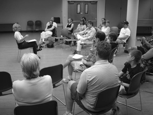 Photo of a group of parents seated in a half circle surrounding a seated speaker.