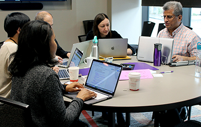 Participants take notes on their laptops while discussing.