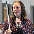 Postdoctoral researcher Cynthia Bennett holds her cane and a microphone while presenting.