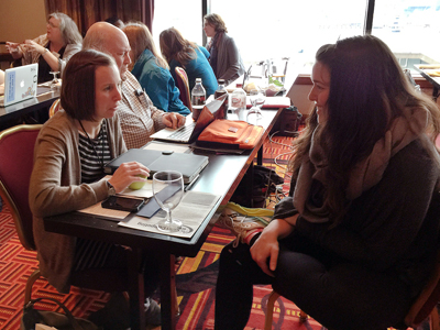 Two women at a table talking while others talk around them.