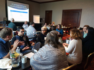 A room of people watching a presentation at the AccessCS10K CBI.