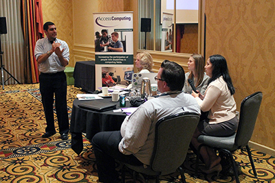 A speaker signs to a table of people during a presentation. A speaker signs to a table of people during a presentation.