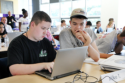 Two students working together on a computer.