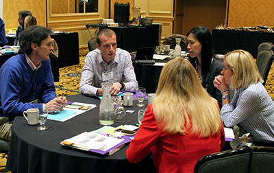 Participants sit around a table talking. Participants sit around a table talking.