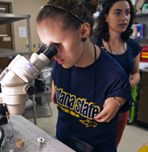 A student with a mobility impairment uses a microscope in a lab