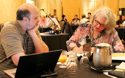 One participant writes down ideas while discussing ideas with another participant.