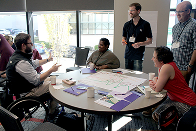 A group listens to one participant explain an idea at the AccessEngineering capacity building institute.