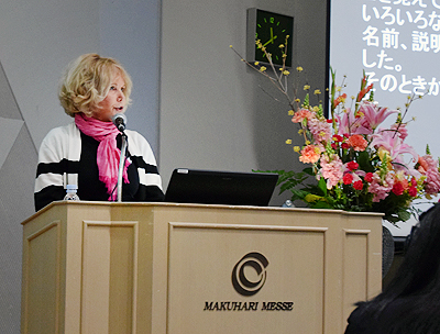 Sheryl Burgstahler speaking at a podium at the Open University of Japan's annual symposium on higher education.