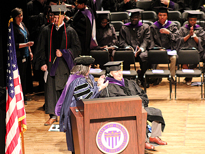 Conrad Reynoldson moving around the podium to receive his diploma.