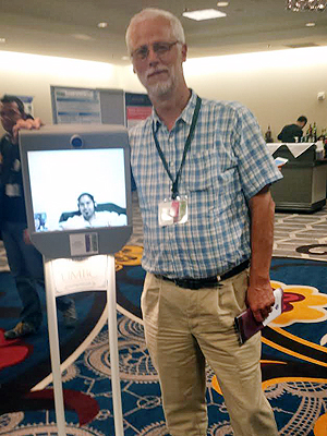 Richard Lander standing with a Beam Robot with Kavita on the front screen.