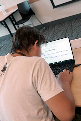 A student uses a screen reader and enlarged text to code. A student uses a screen reader and enlarged text to code.