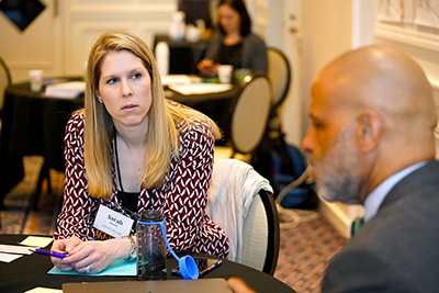 A participant listens to another at her table.