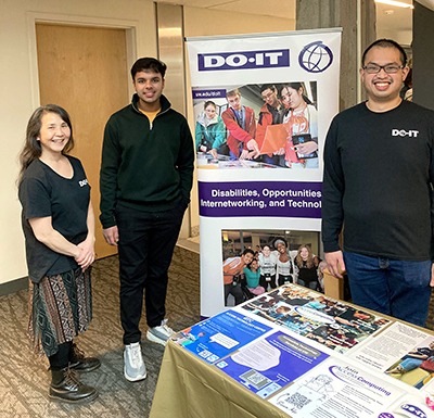 Andrea, Aditya, and Dustine stand in front of the DO-IT Banner. Andrea, Aditya, and Dustine stand in front of the DO-IT Banner.