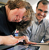 A mentor works with a student on a computing project