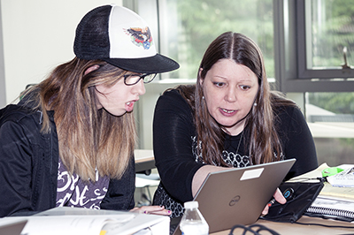 A staff member helps a student on the computer.