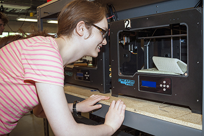 A student excitedly watches a 3D printer in action.
