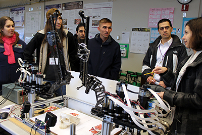 Participants stand around a robotics display to discuss accessibility in practice.