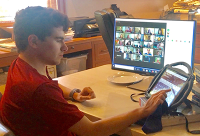 DOITNews-Nov2020-17.jpg Student watching zoom on computer and working on iPad
